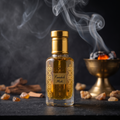 A small glass bottle of Finashk Mask with a shiny gold cap and gold decorative patterns on the label, filled with amber-colored liquid. The bottle is set on a dark slate surface with scattered amber pieces, a smoky incense burner, and smoke rising in the background.
