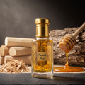 A clear glass perfume bottle filled with golden amber liquid, featuring a gold cap and ornate gold geometric patterns on the front label. The label reads 'Finashuk Mask'.
